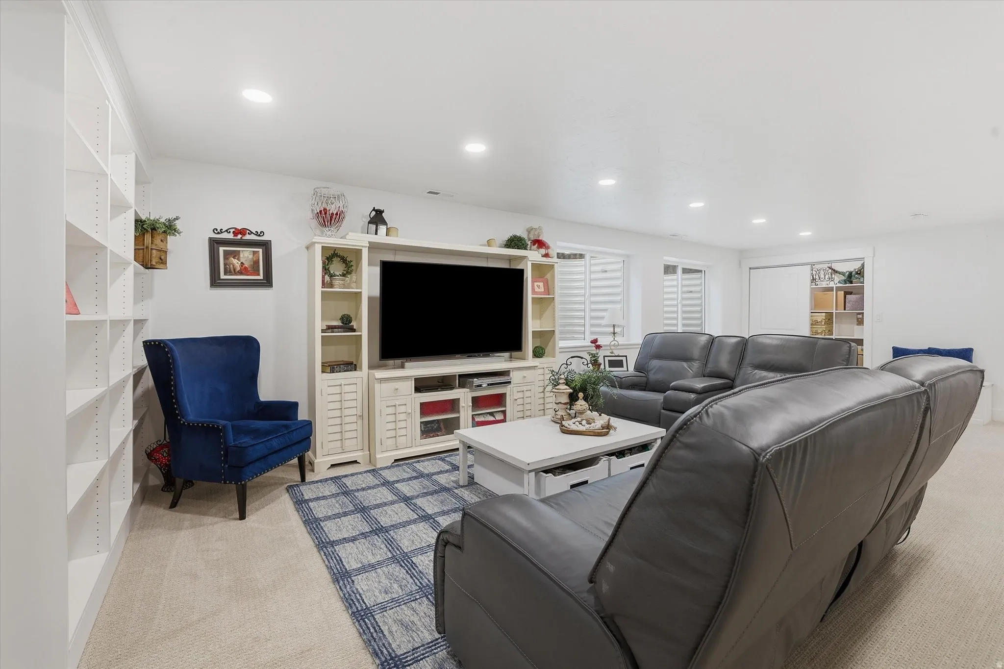 Spacious living area featuring neutral carpeting, a large built-in media console, recessed lighting, and extensive built-in shelving