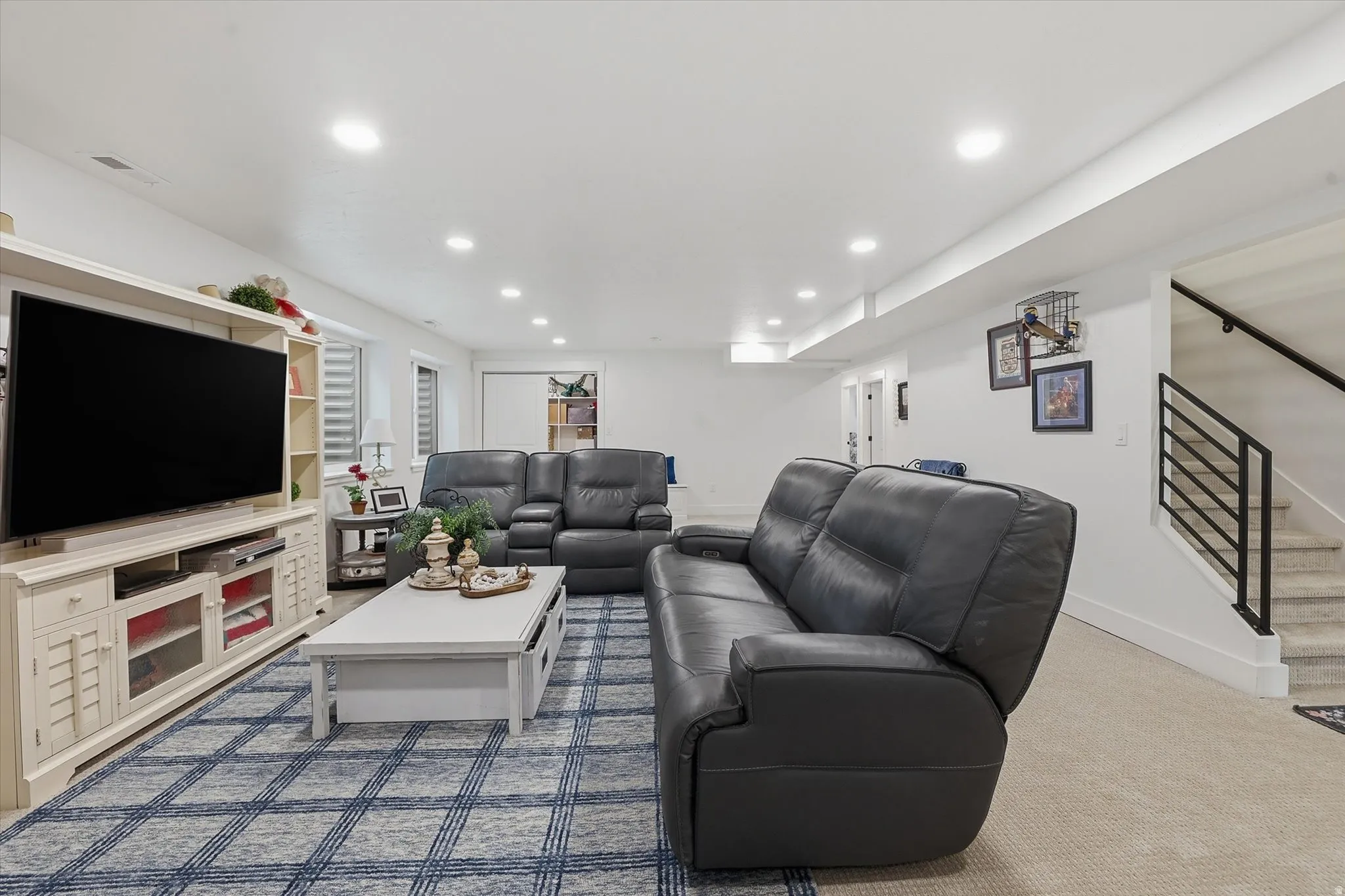 Finished lower-level living space featuring recessed lighting, light-toned carpeting, and a built-in media console with open shelving