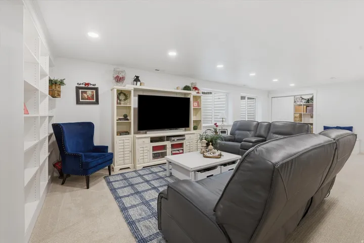 Spacious living area featuring neutral carpeting, a large built-in media console, recessed lighting, and extensive built-in shelving