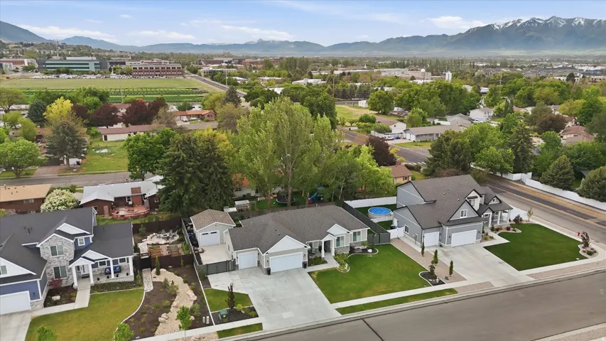 Modern residential streetscape featuring a single-story property with a two-car garage, mature landscaping, and a fenced backyard