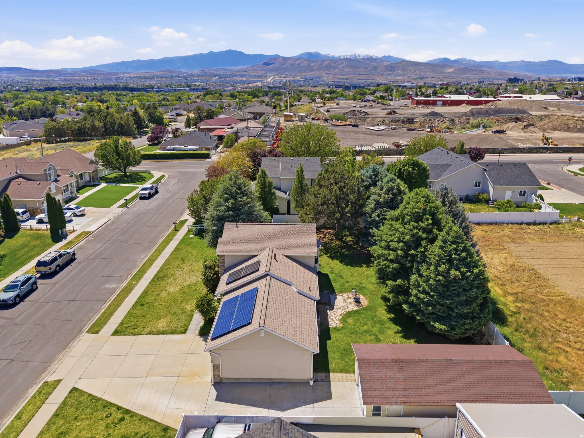 Suburban residence featuring solar panels on the roof, a concrete driveway, and a stone patio