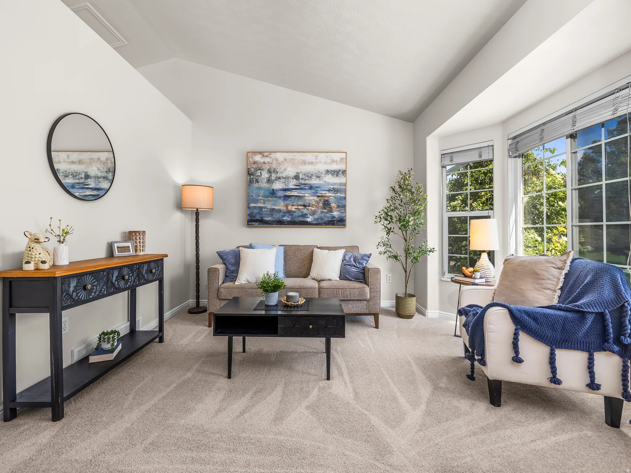 Living room featuring a vaulted ceiling, neutral wall paint, and light-toned carpet flooring