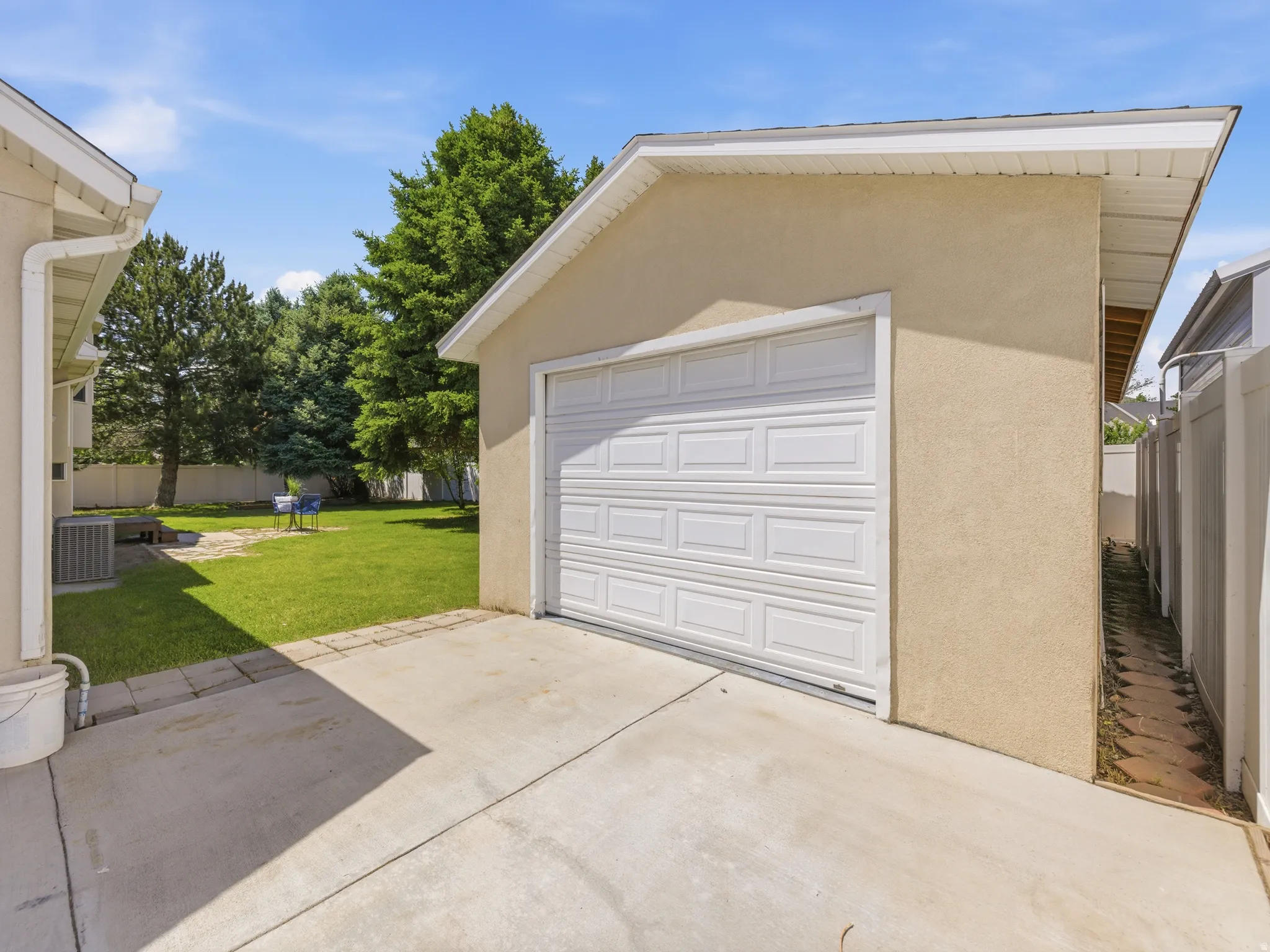 Detached garage with a paneled white door and stucco exterior