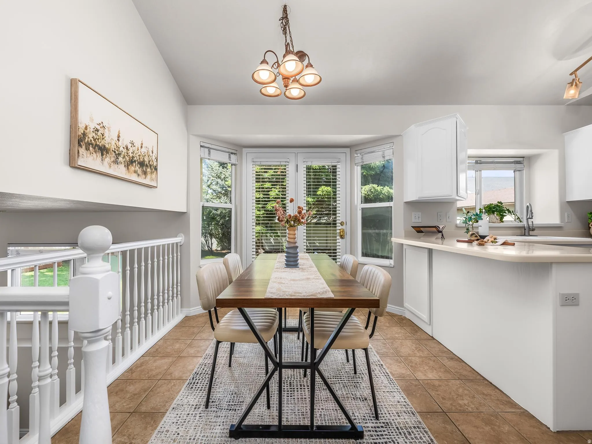 Open-concept dining area featuring a bay window, tile flooring, and a contemporary chandelier