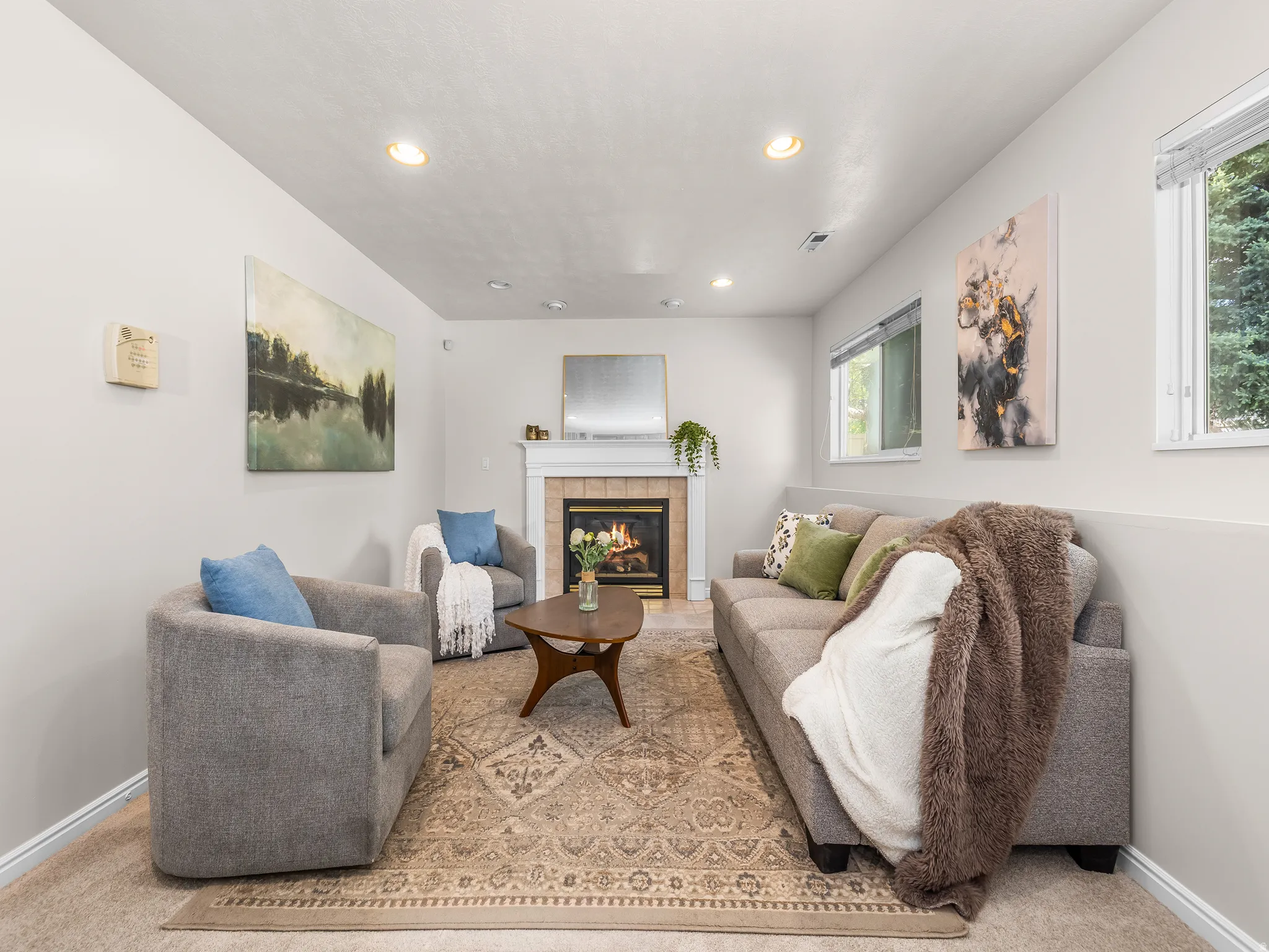 Living area featuring a fireplace with a white mantel, recessed lighting, and wall-mounted windows