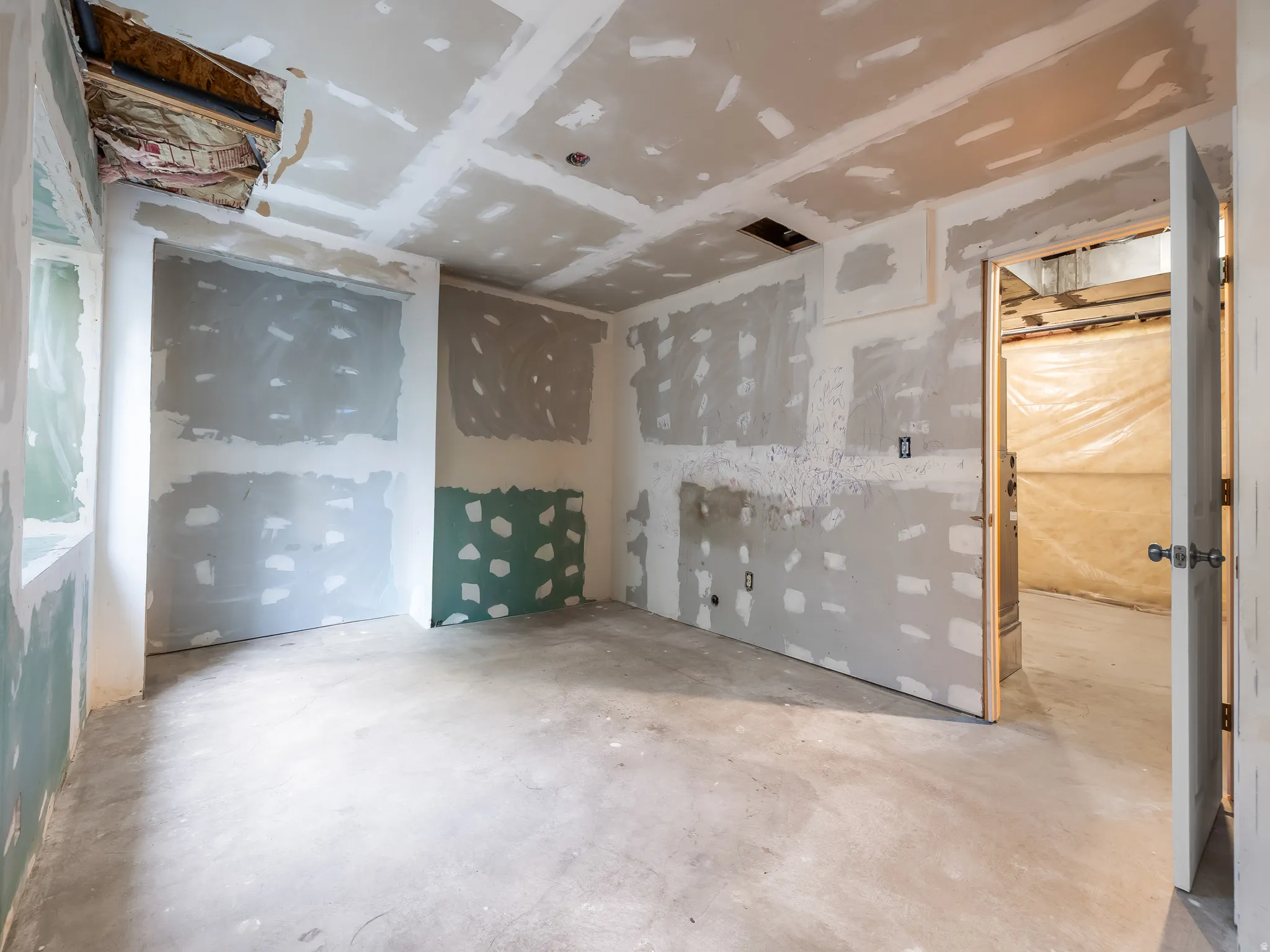 Unfinished interior space featuring drywall installation, exposed ceiling joists, and a concrete floor