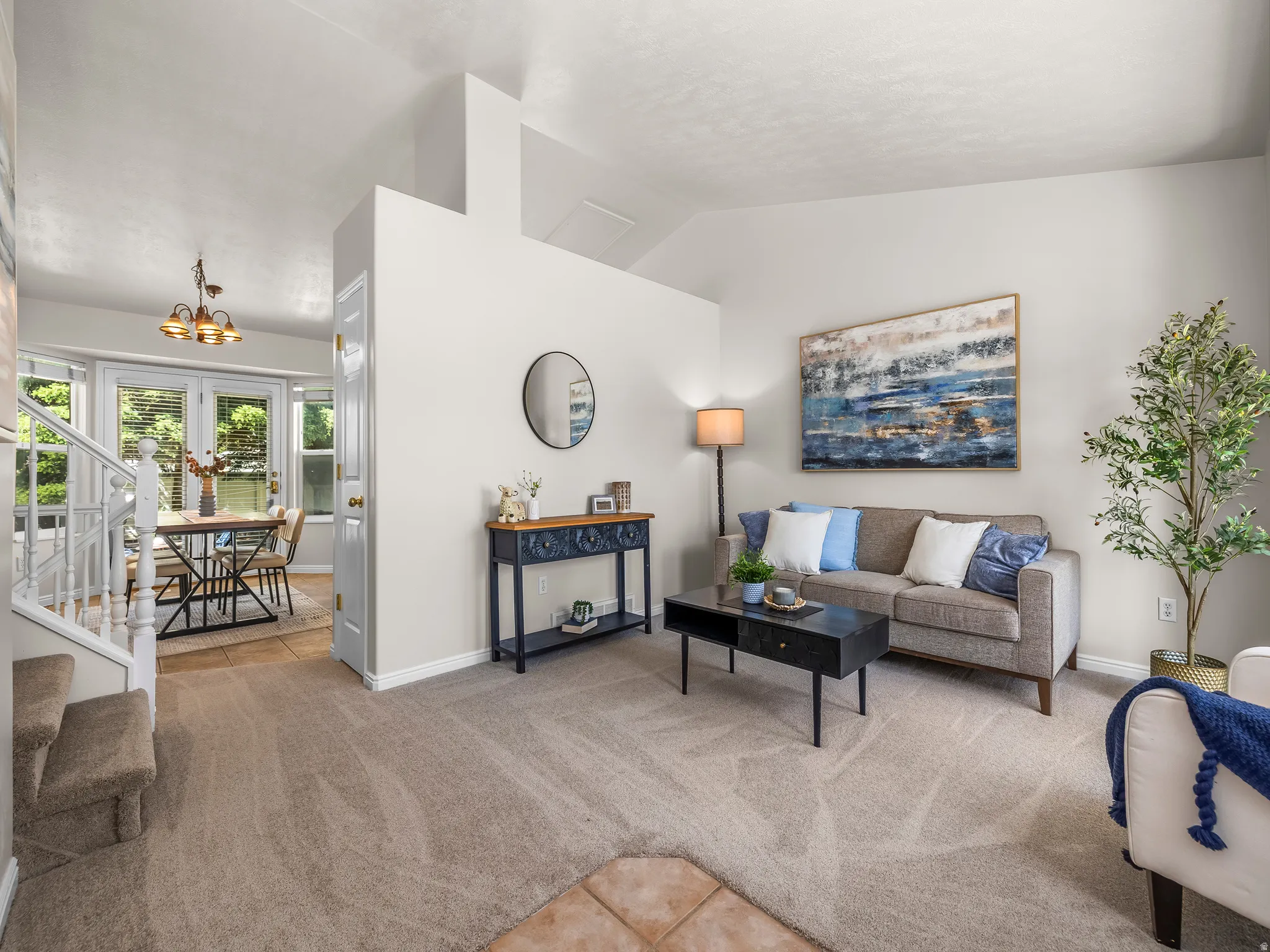 Living area featuring vaulted ceilings, light neutral wall paint, and plush carpet flooring