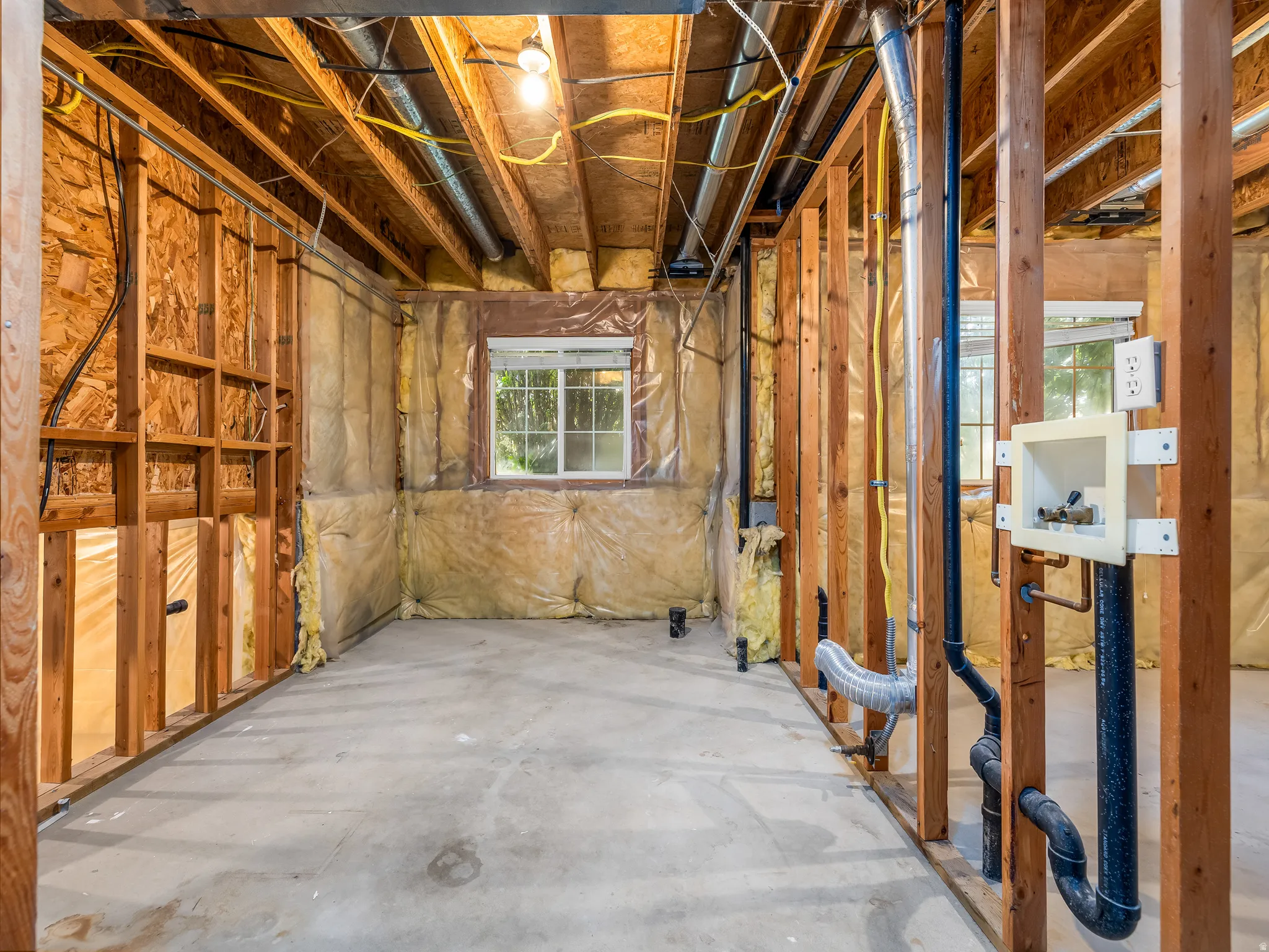 Unfinished basement with concrete flooring and exposed wood framing