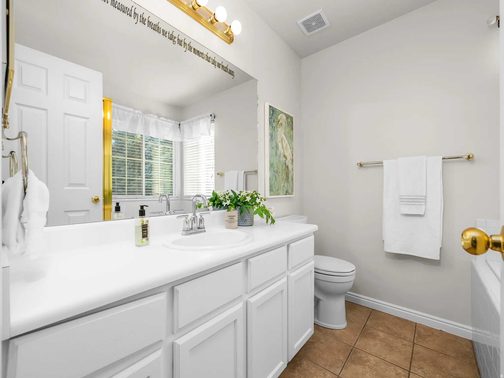 White vanity with integrated sink, brushed nickel faucet, large wall mirror, and brass light fixture