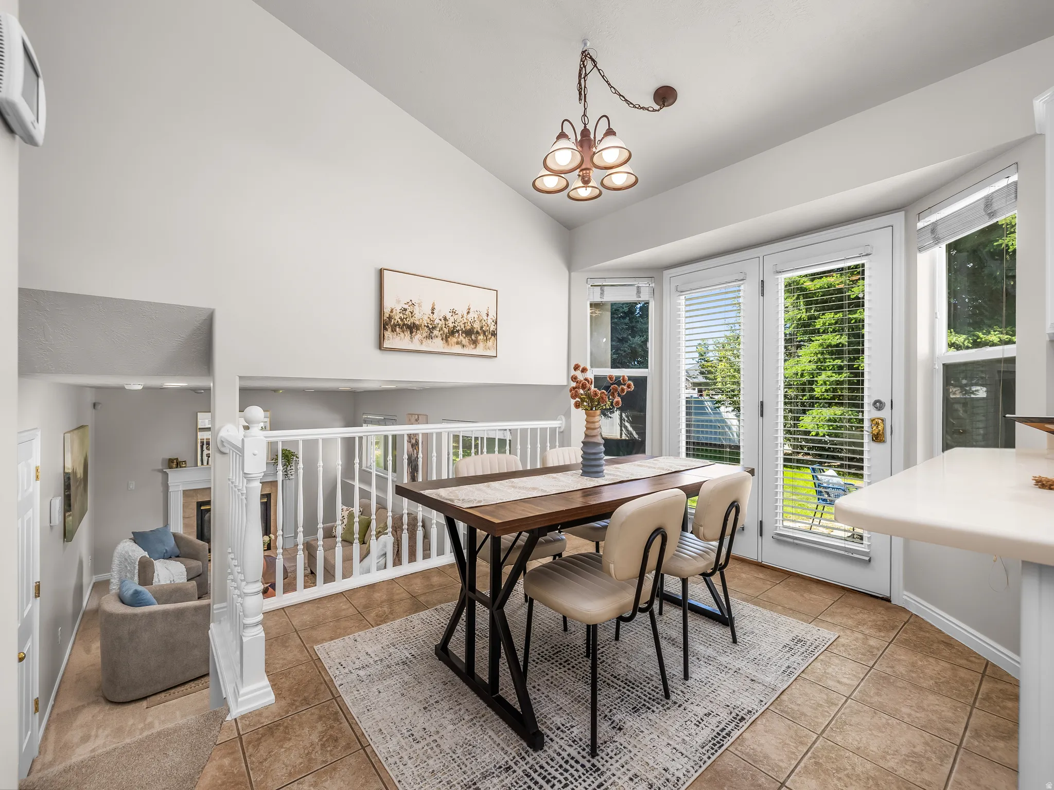 Dining area featuring tile flooring, a vaulted ceiling, and a multi-light chandelier