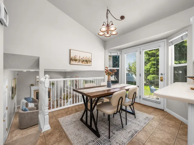 Dining area featuring tile flooring, a vaulted ceiling, and a multi-light chandelier