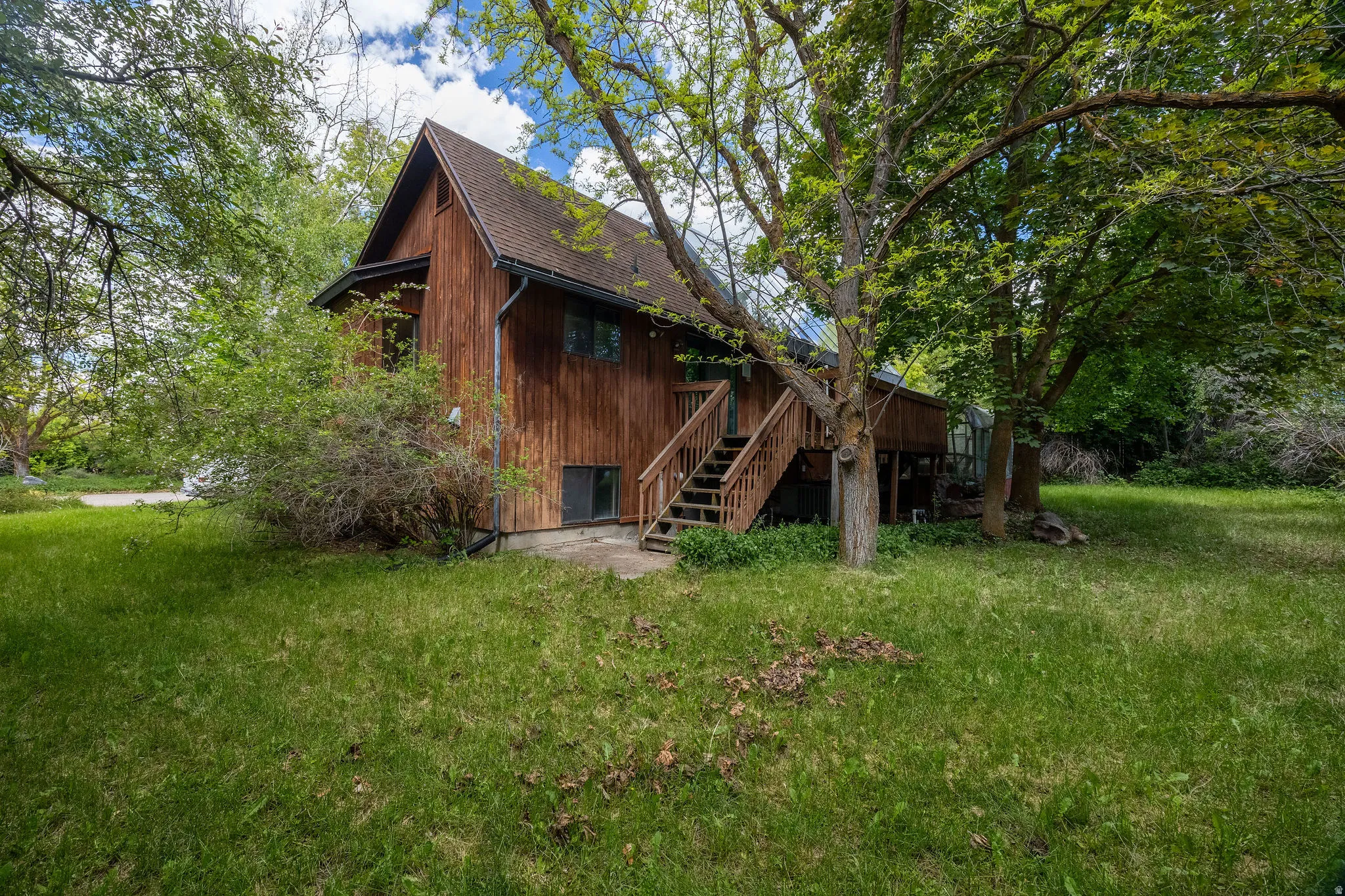 Wood-sided A-frame structure featuring a raised wood deck with stairs