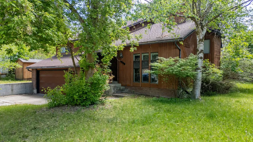 Wood-sided exterior featuring multiple windows and a brown garage door