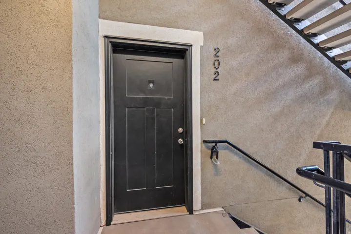 Black panel door with white trim set into a textured stucco wall