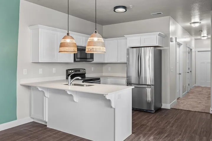 Kitchen featuring white cabinetry, stainless steel appliances, a center island with sink, and pendant lighting