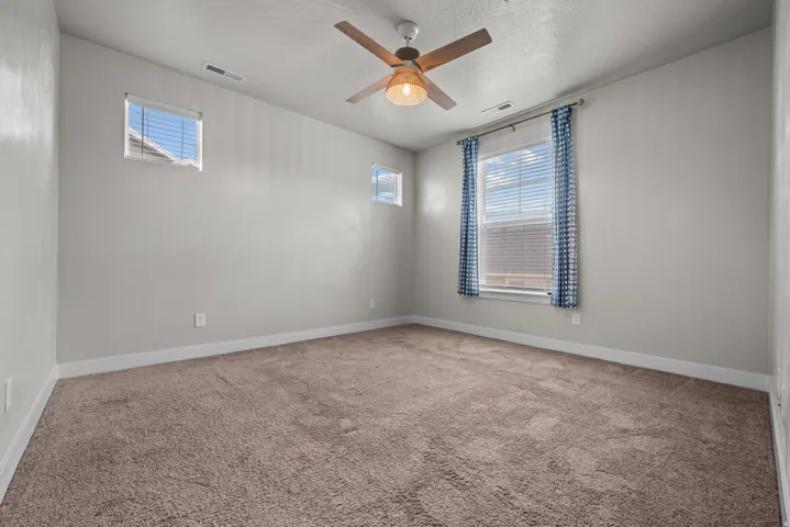 Spacious interior featuring neutral wall paint, plush carpet flooring, and a ceiling fan with integrated lighting