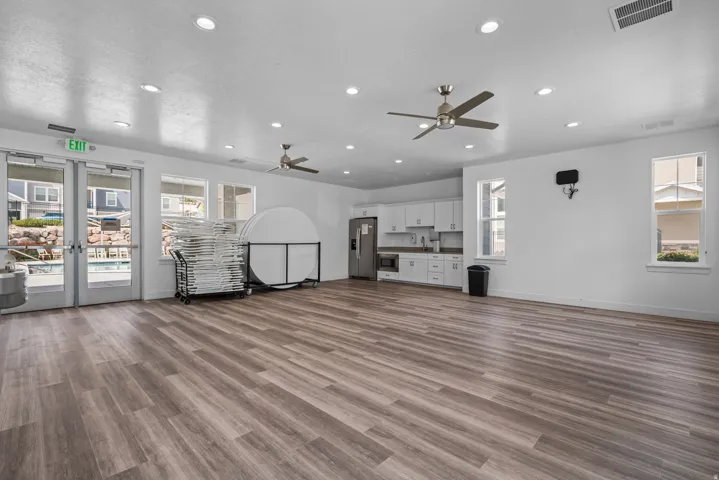 Spacious communal area featuring extensive wood-finish flooring, recessed lighting, and multiple ceiling fans