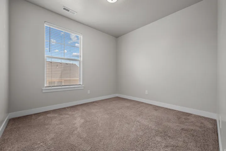 Neutral-toned room featuring a single window with horizontal blinds, light gray walls, and brown carpet flooring