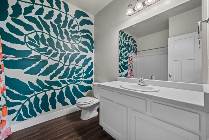 Bathroom featuring a vanity with an integrated sink and chrome faucet, a wall-mounted mirror, and a three-light fixture