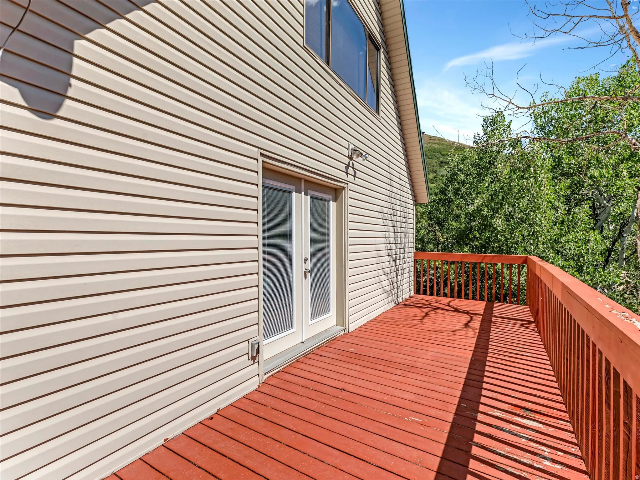 Spacious outdoor deck with a red-stained wood surface and matching wood railings