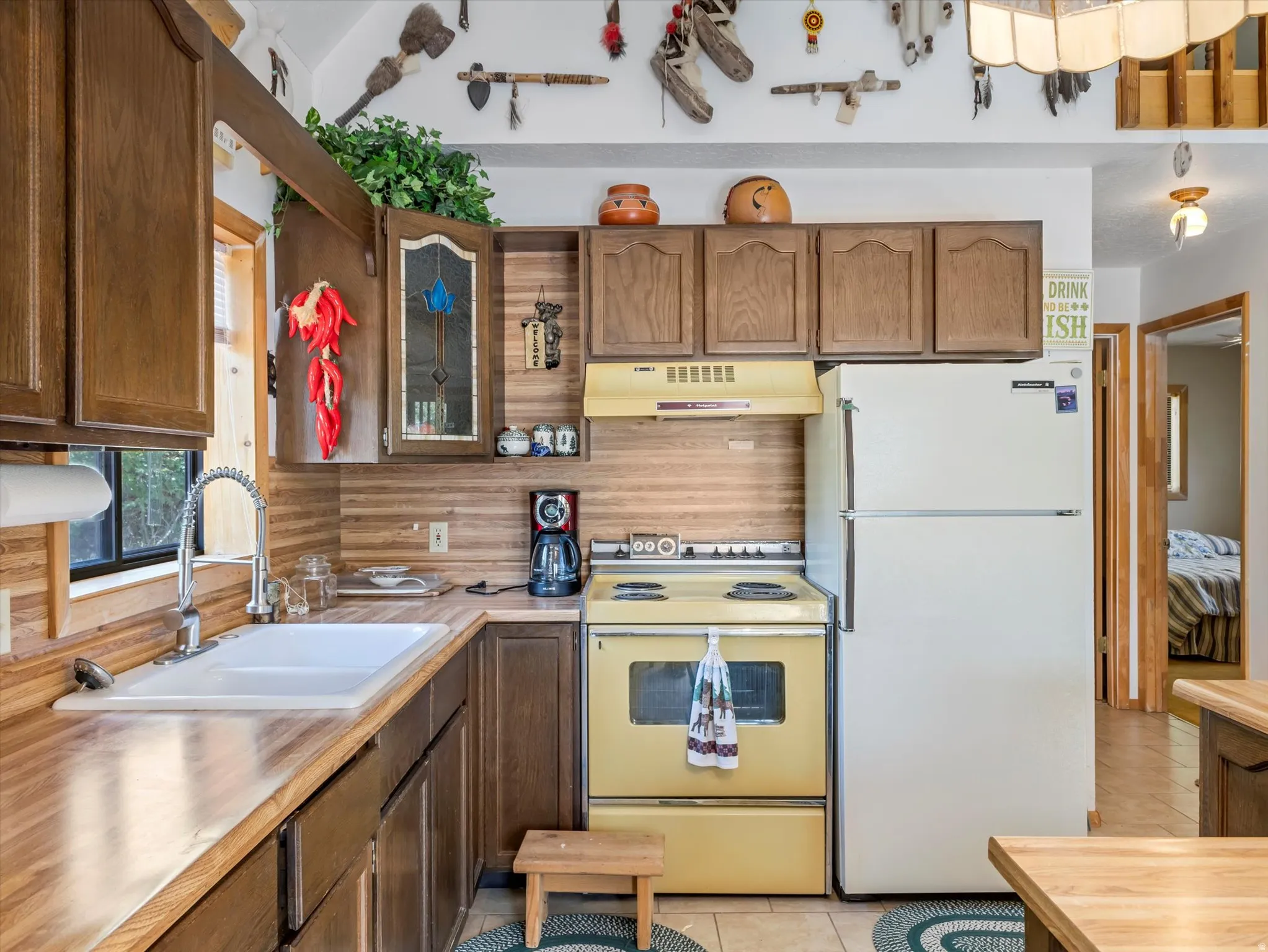 Kitchen featuring wood-finish countertops and backsplash, coordinating wood cabinetry, a white drop-in sink with a gooseneck faucet, and light-toned floor tiling