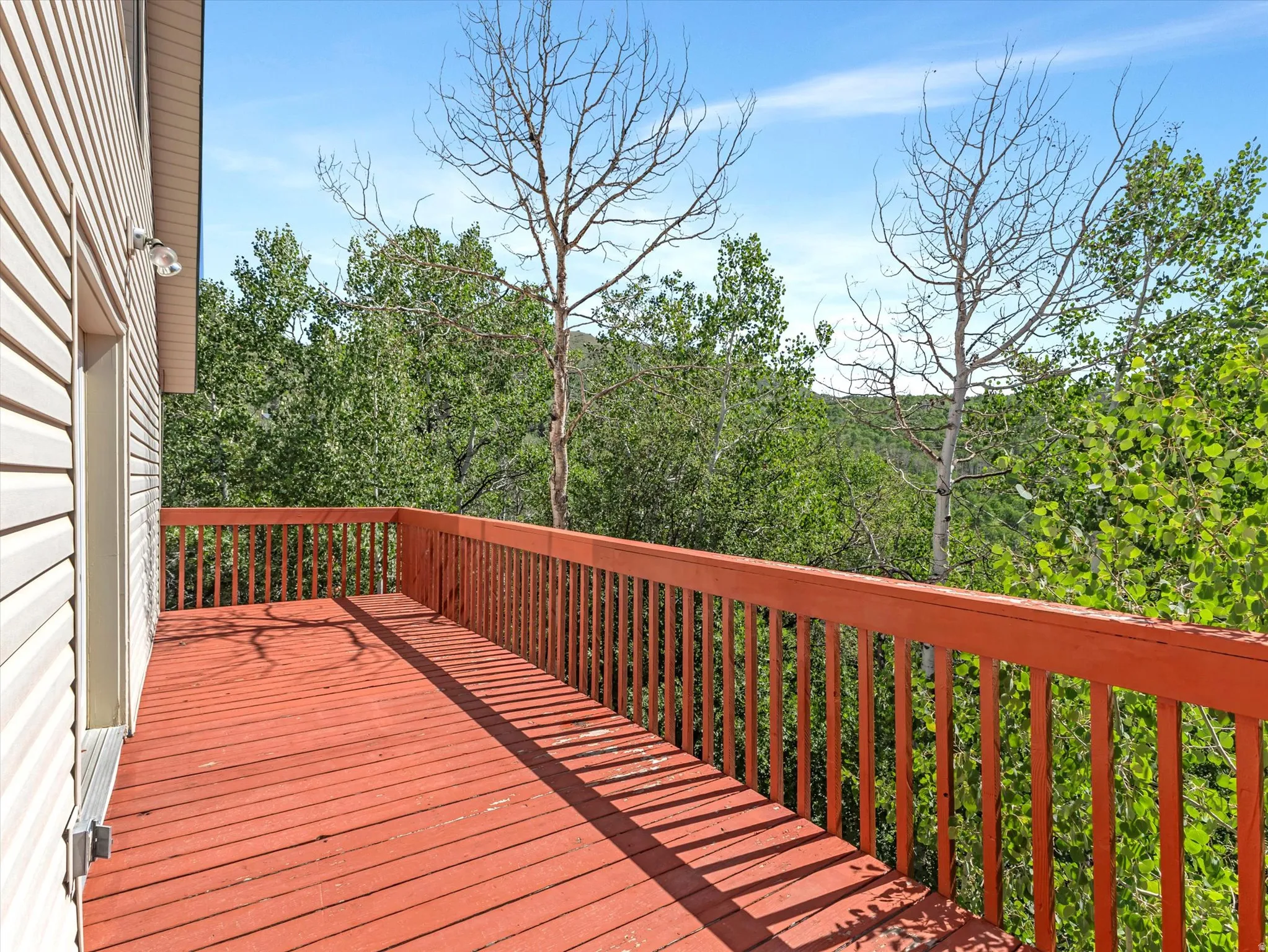 Expansive outdoor deck with a red-stained wood surface and matching wood railing