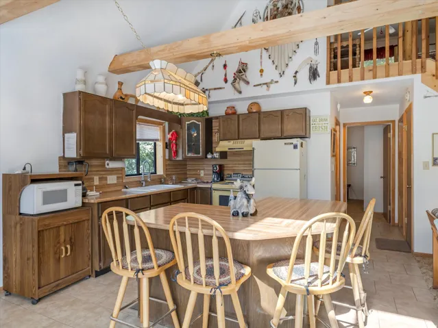 Kitchen featuring wood-finish cabinetry, tile flooring, a built-in double basin sink, and an island with seating