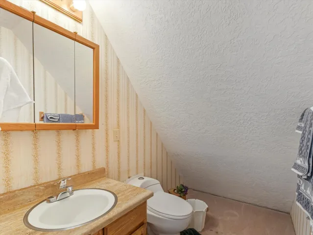 Bathroom featuring a wood-framed medicine cabinet with mirrored doors, a single vanity with a white oval sink, and a light-toned countertop