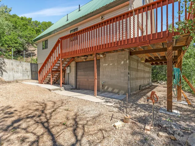 Exterior featuring a green metal roof, light-toned siding, and a wooden deck with railing
