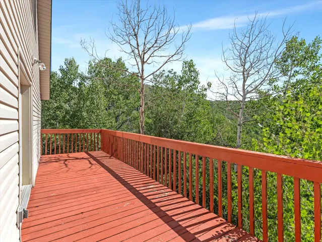 Expansive outdoor deck with a red-stained wood surface and matching wood railing