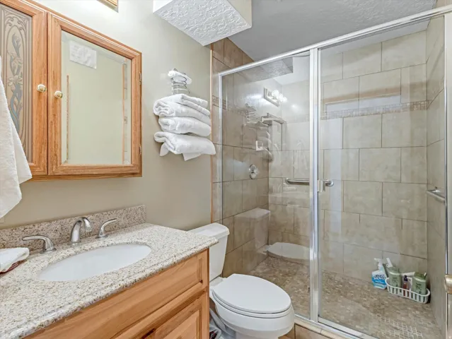 Bathroom featuring a glass-enclosed shower with tiled walls and a pebble-finish floor