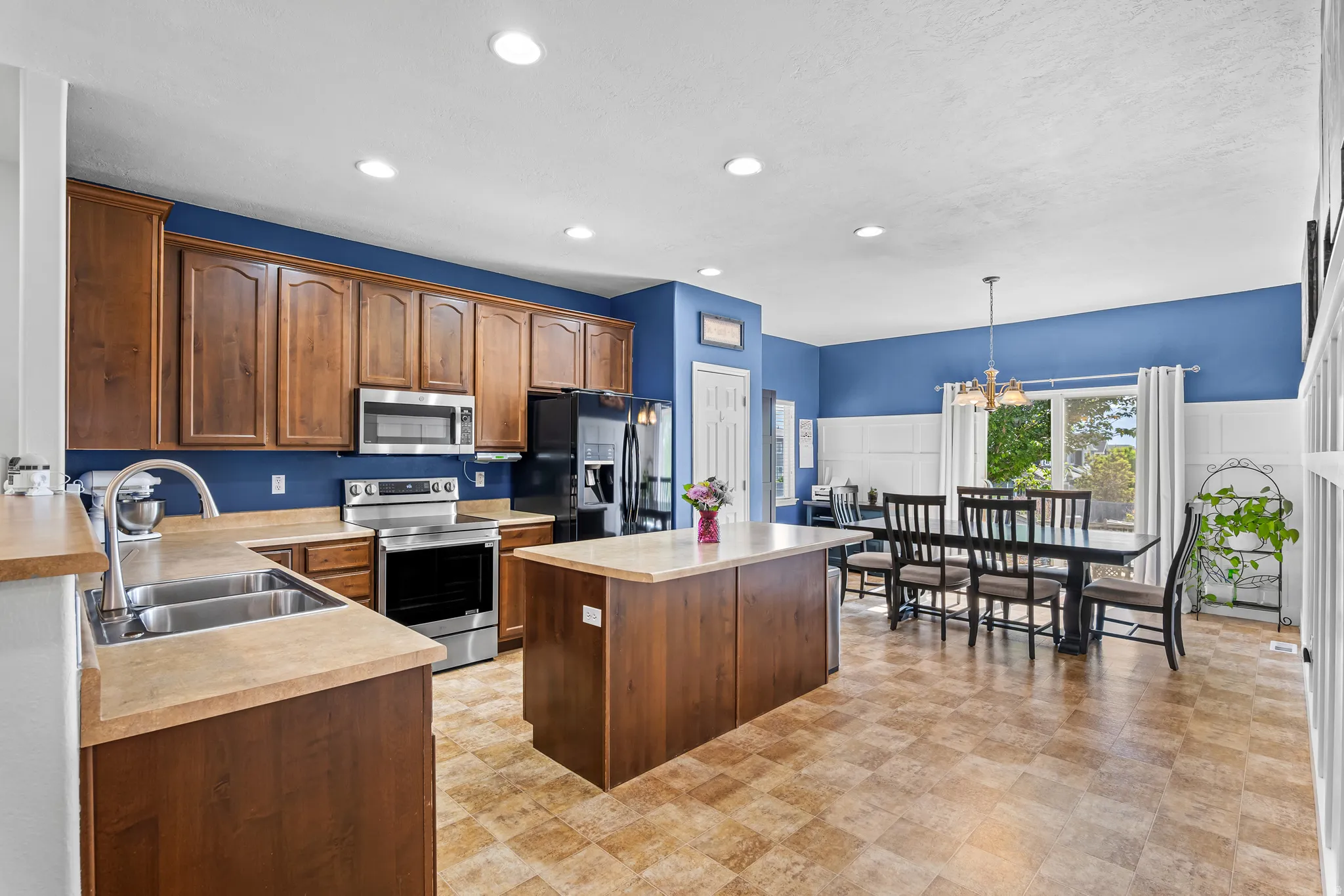 Expansive kitchen and dining area featuring wood cabinetry, stainless steel appliances, a center island, and wood-finish flooring