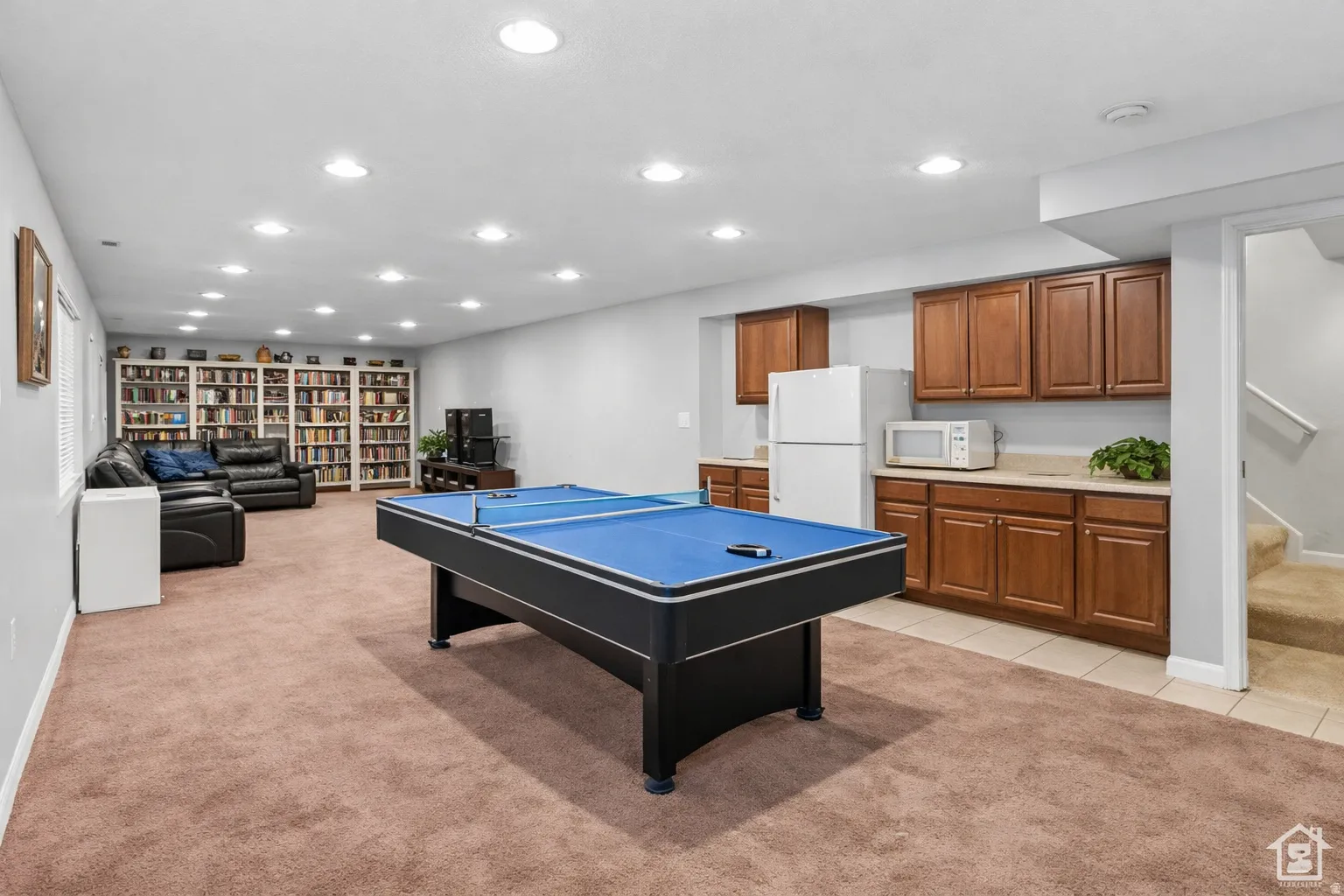 Spacious lower level featuring plush carpet, extensive recessed lighting, and a built-in wet bar with cabinetry and countertop space