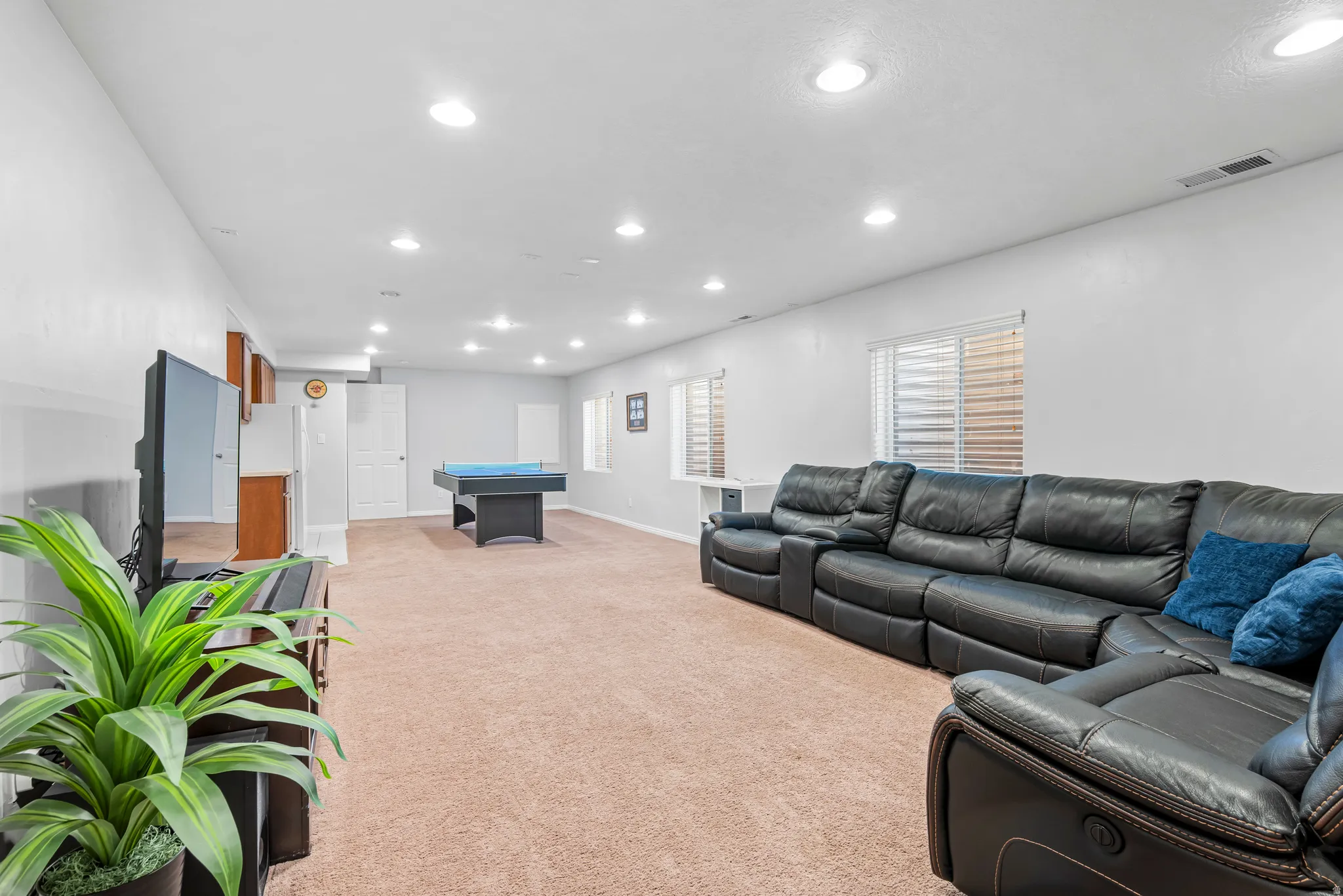 Spacious carpeted room featuring recessed lighting, multiple windows with blinds, built-in cabinetry, and white paneled doors
