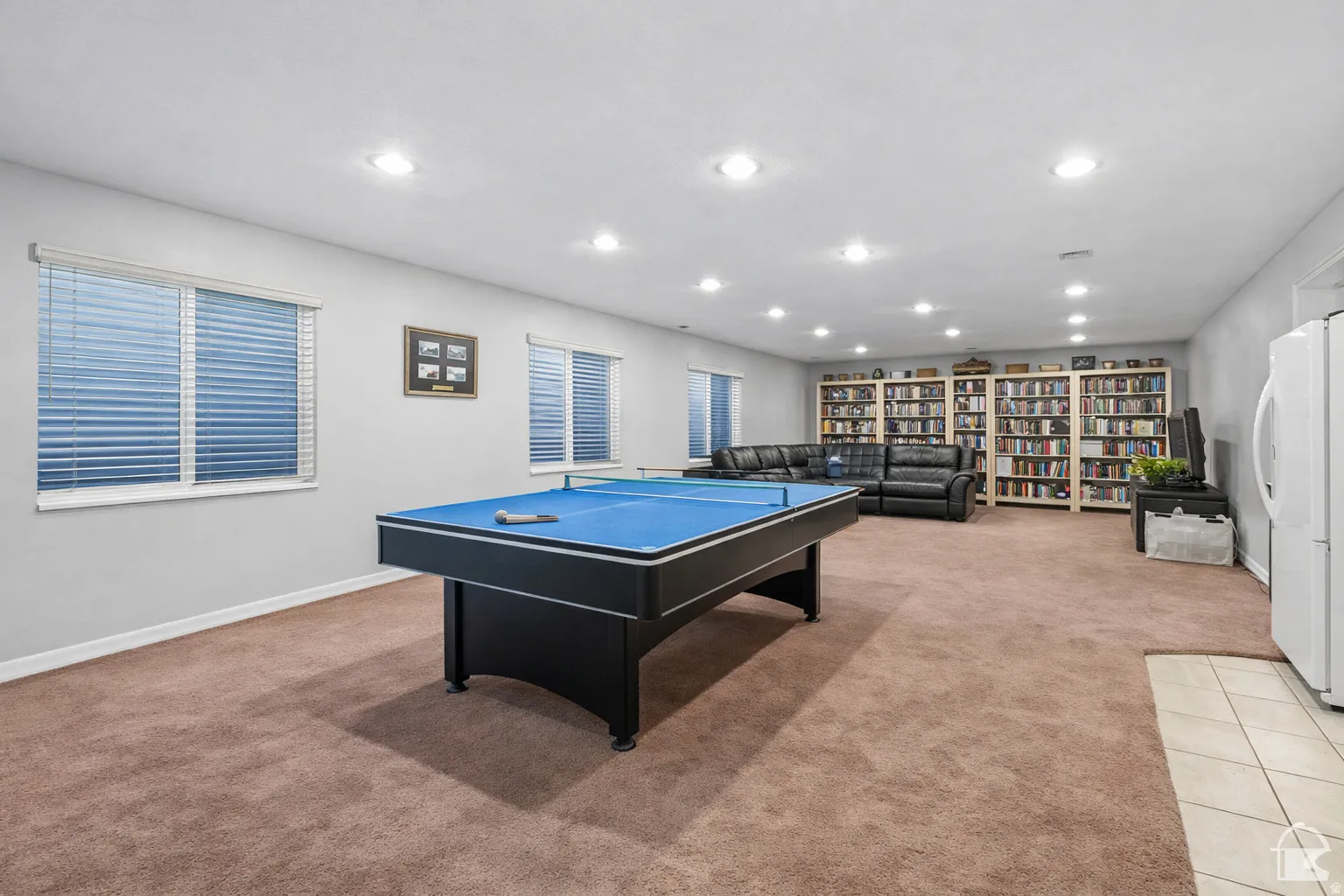 Spacious recreation room featuring recessed lighting, a neutral color palette, and two windows with blinds
