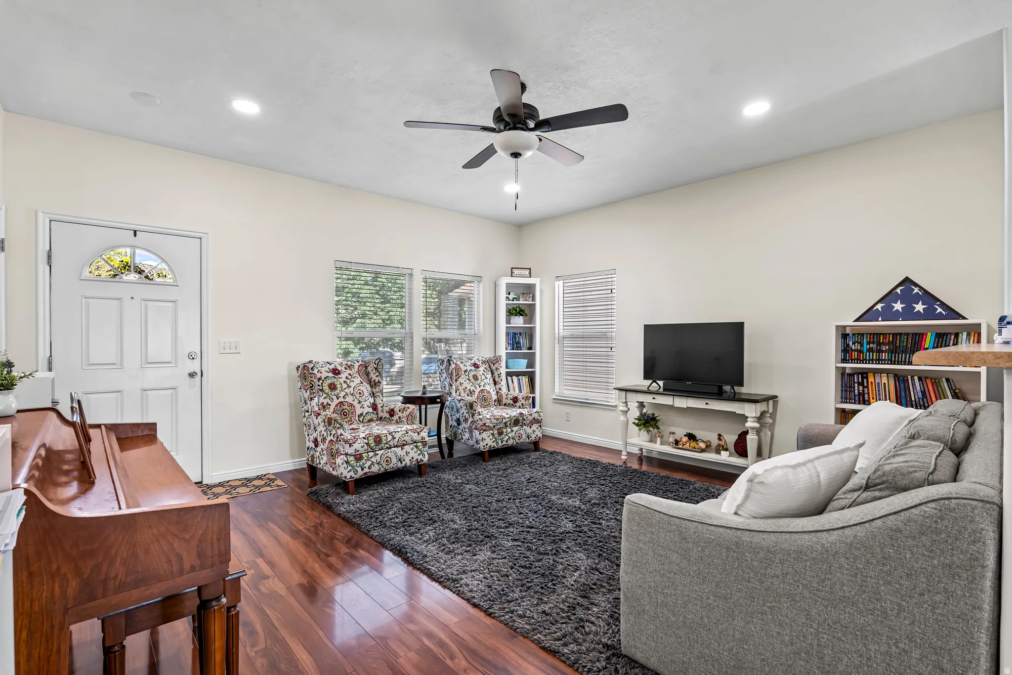 Living area with wood-finish flooring, recessed lighting, and a ceiling fan