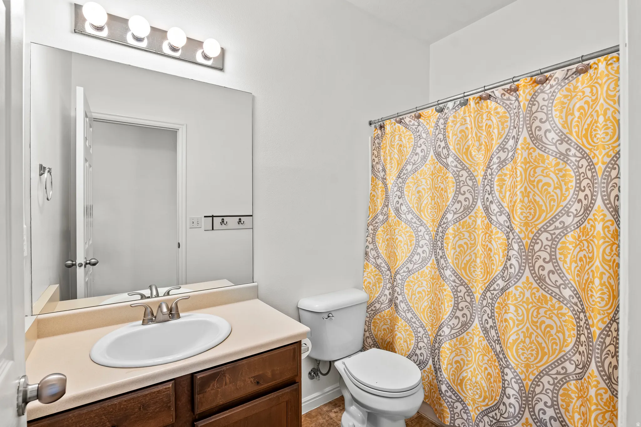 Bathroom featuring a single vanity with a laminate countertop, dark wood-finish cabinetry, a white oval sink, and a brushed nickel faucet
