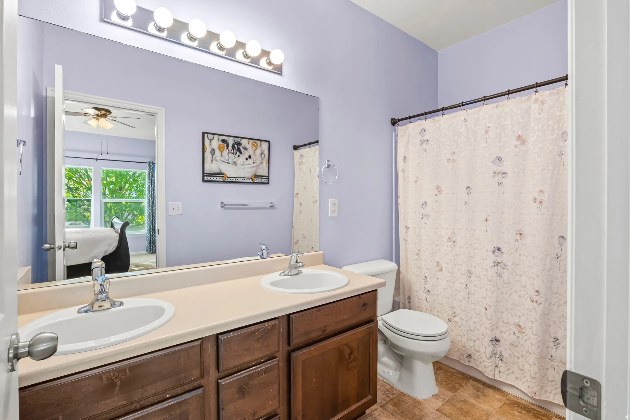 Bathroom featuring a double vanity with integrated sinks, a beige countertop, and wood-finish cabinetry