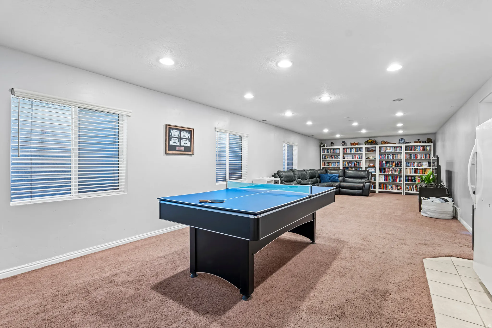 Expansive entertainment room featuring recessed lighting and two large windows with blinds