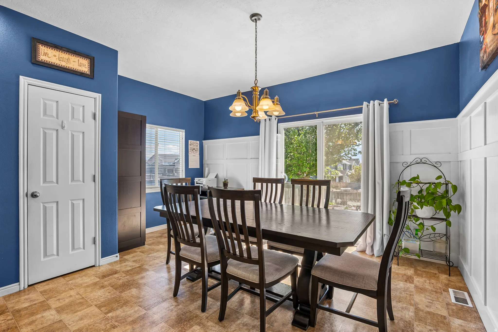 Dining area featuring a sliding glass door, white board and batten wainscoting, and wood-finish flooring