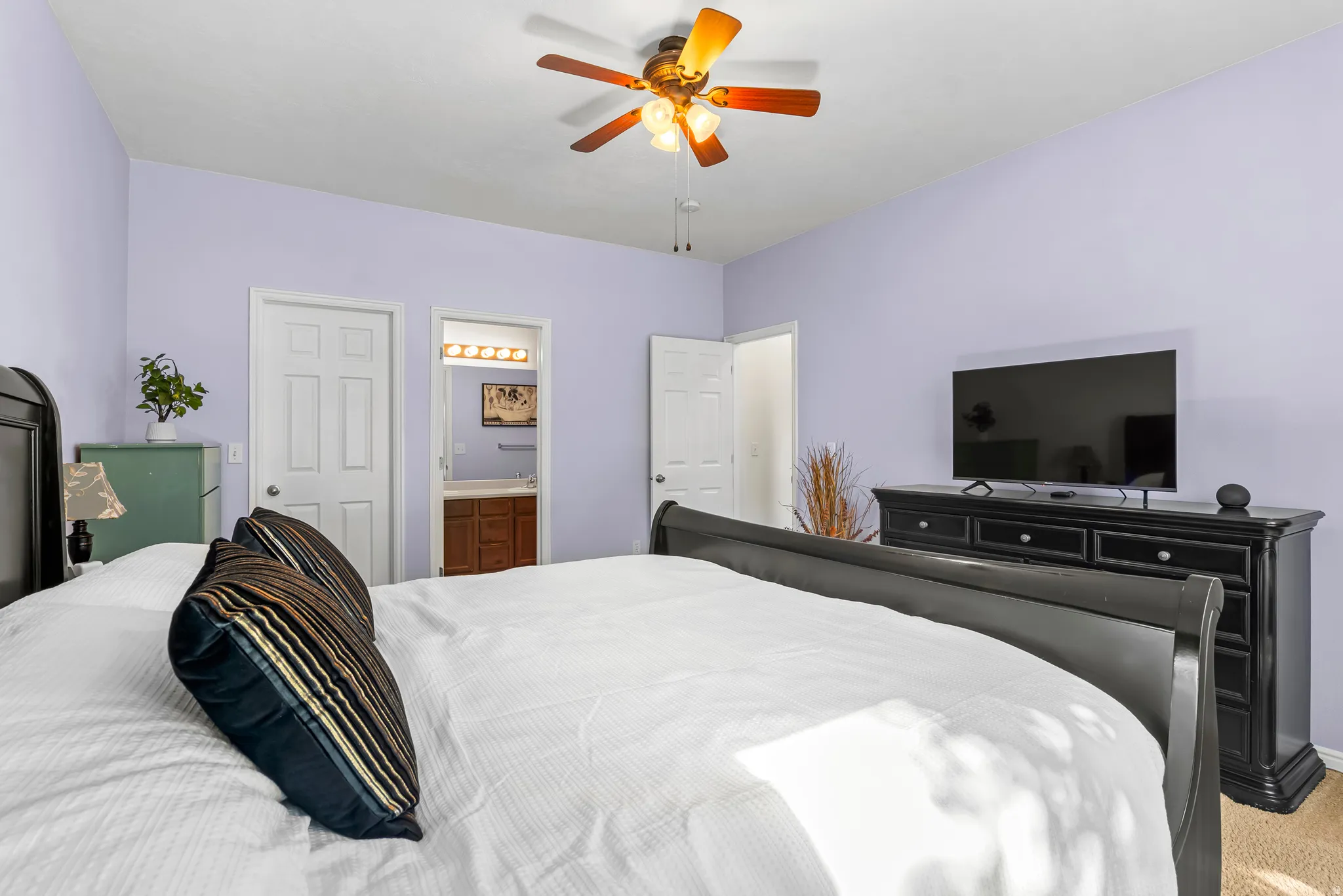 Spacious room featuring light lavender walls, a white ceiling, and a ceiling fan with integrated lighting