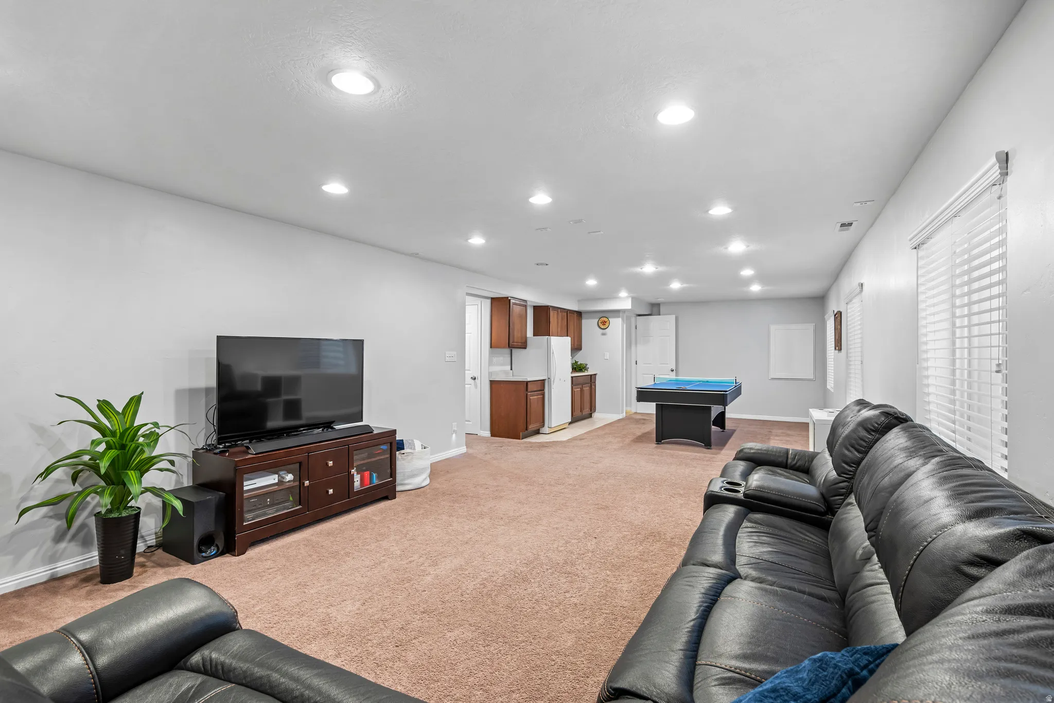 Open-concept recreation area featuring recessed lighting, a built-in wet bar with wood-finish cabinetry, and a dedicated space for entertainment
