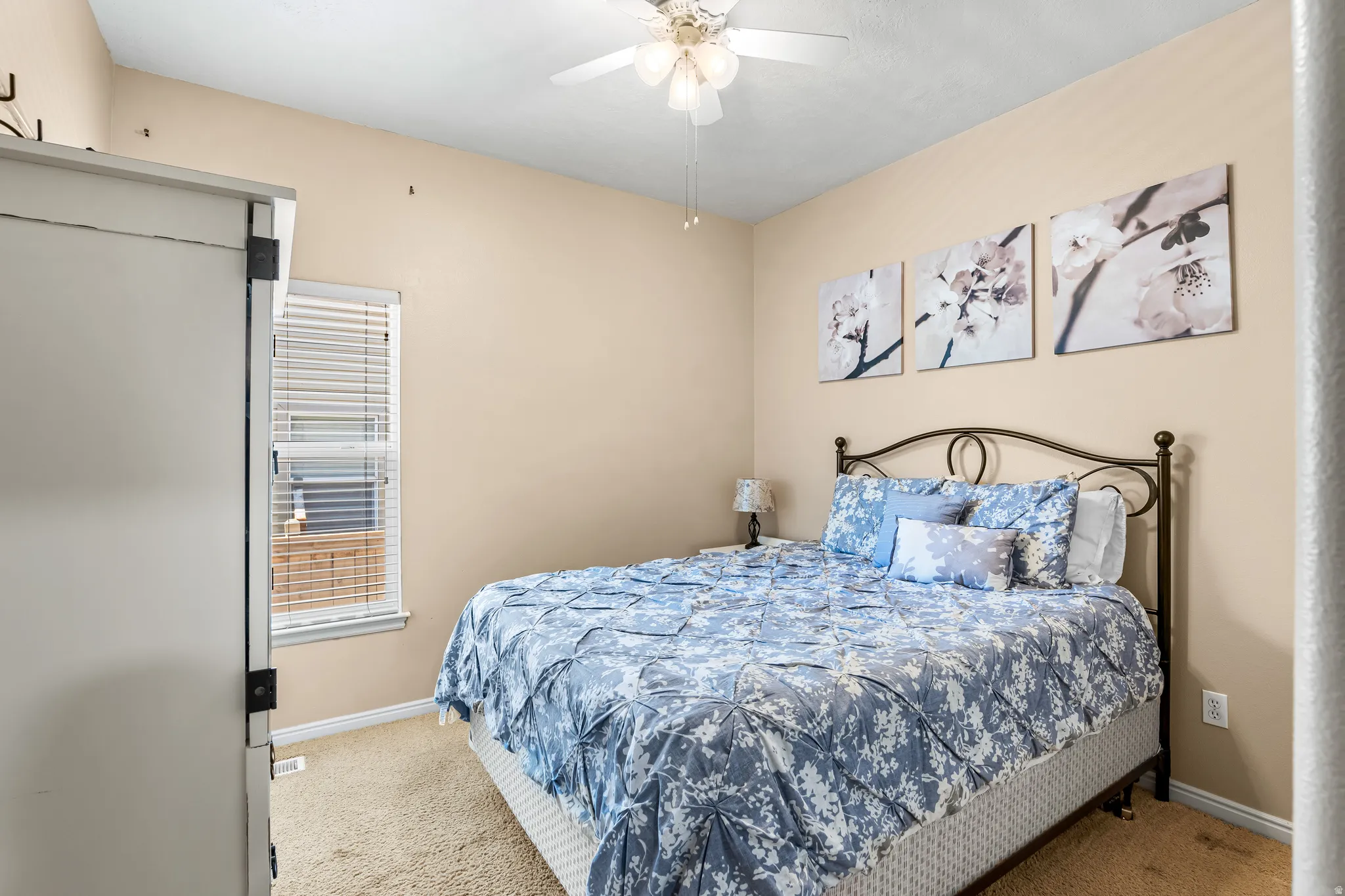Carpeted bedroom with neutral wall color and a ceiling fan with integrated lighting