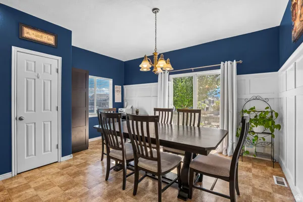 Spacious dining area featuring two-tone walls with white wainscoting and a deep blue upper section