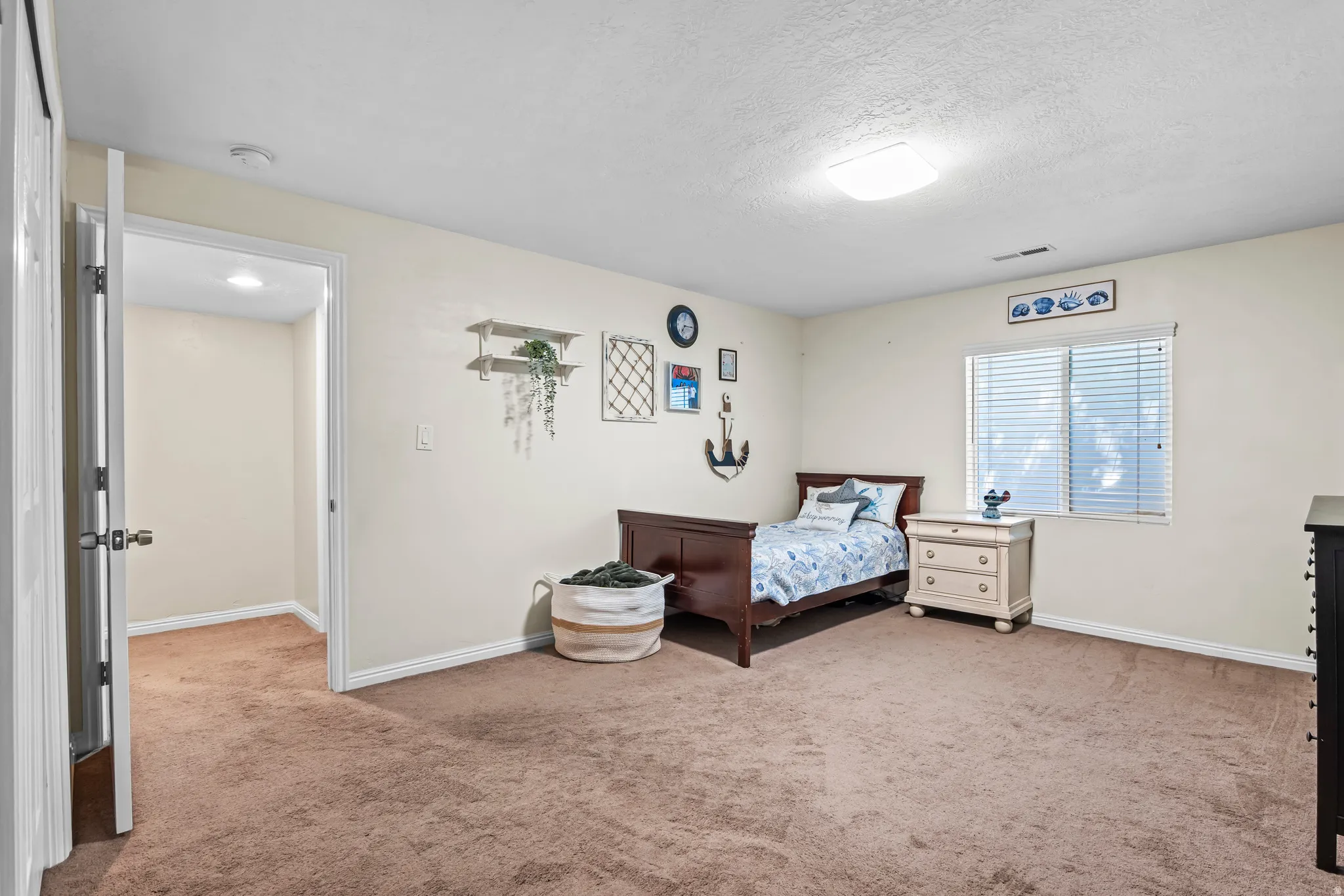 Spacious interior room featuring light-colored walls and brown carpeting