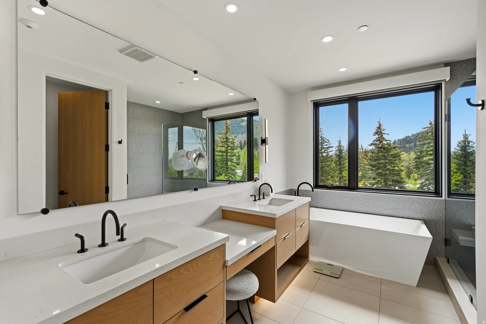 Contemporary bathroom featuring a freestanding tub, dual vanities with integrated sinks, and ample natural light from expansive windows