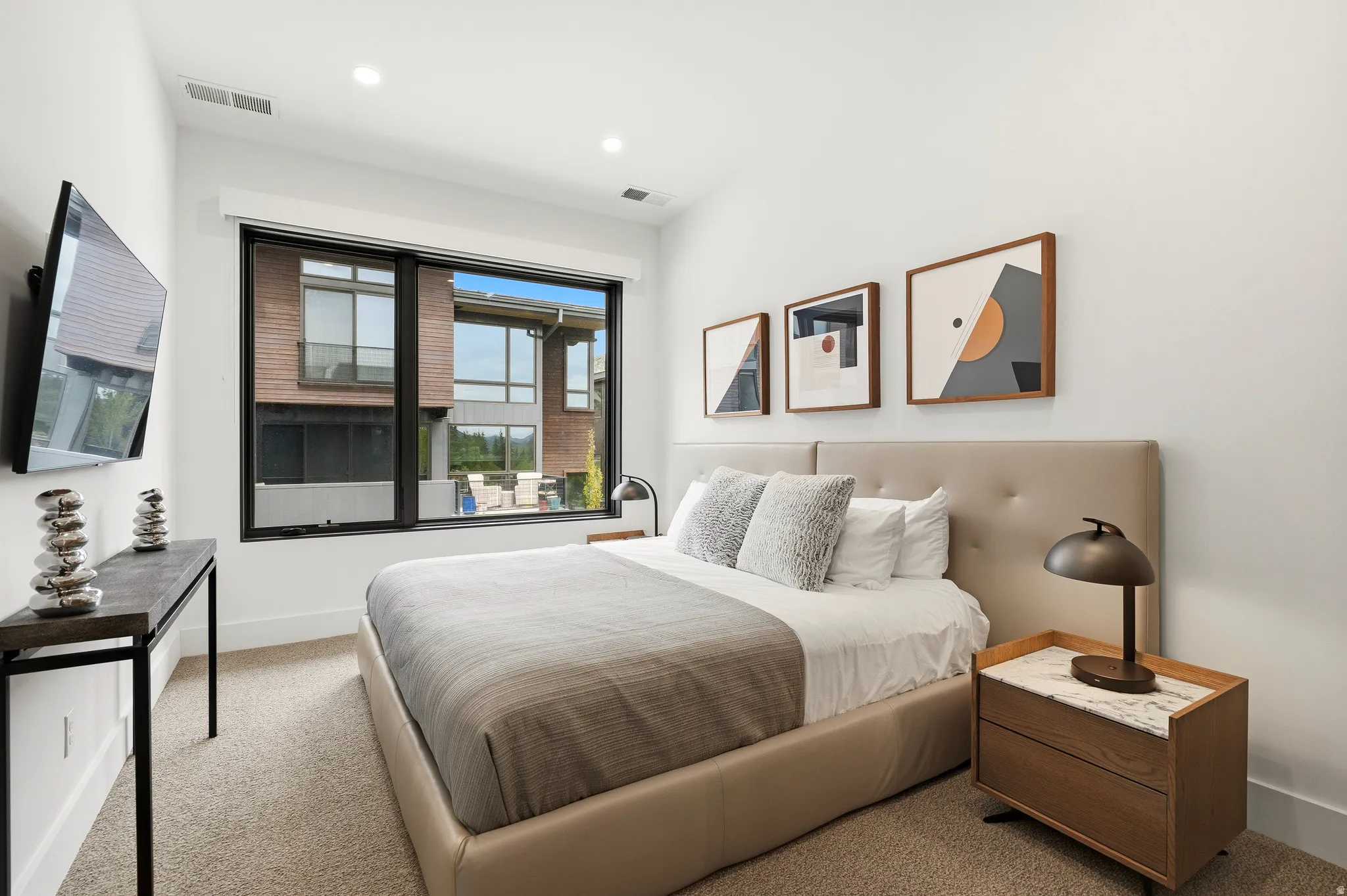 Contemporary bedroom featuring a large picture window, recessed lighting, and neutral wall paint