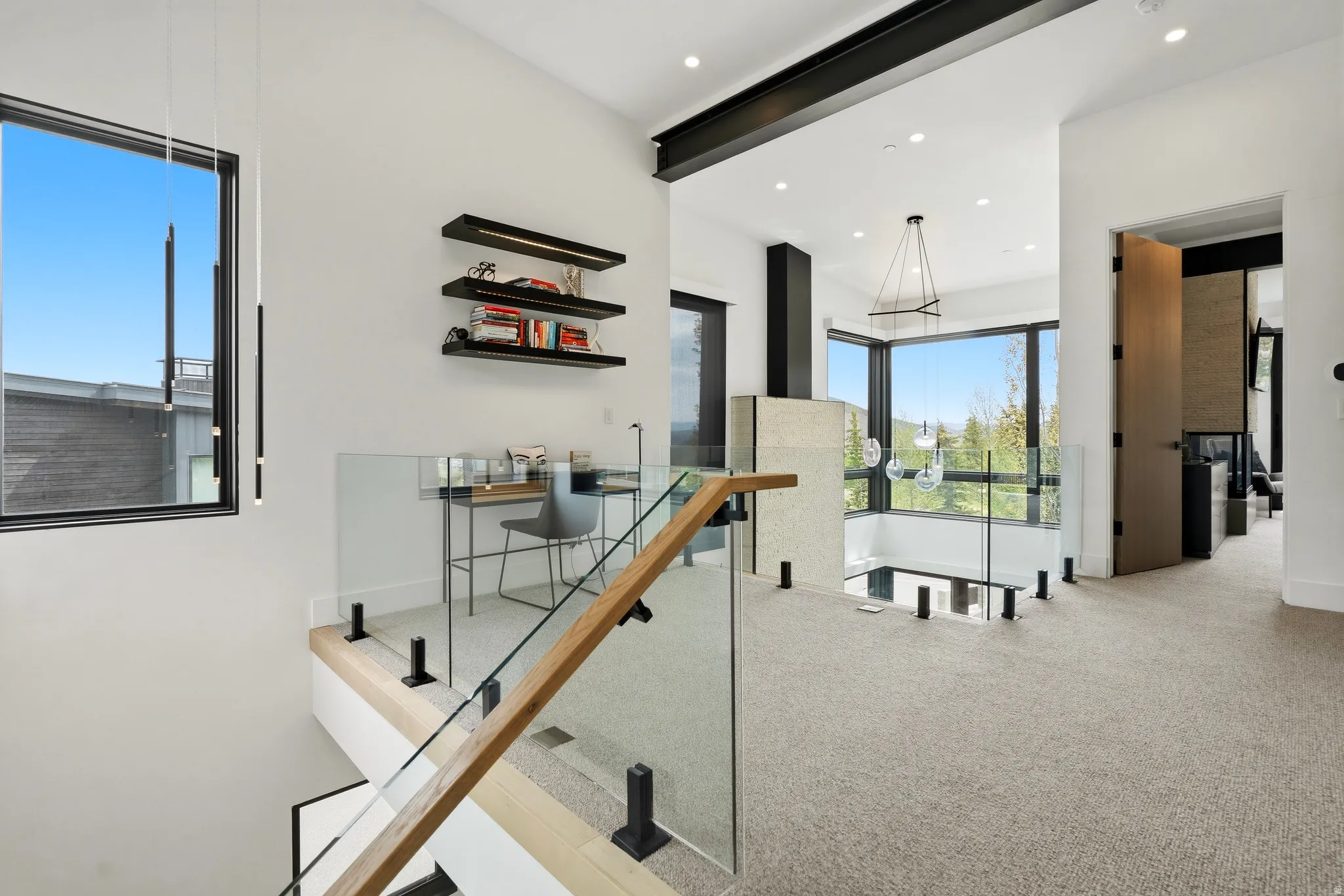 Upper-level landing featuring a glass and wood-finish railing system