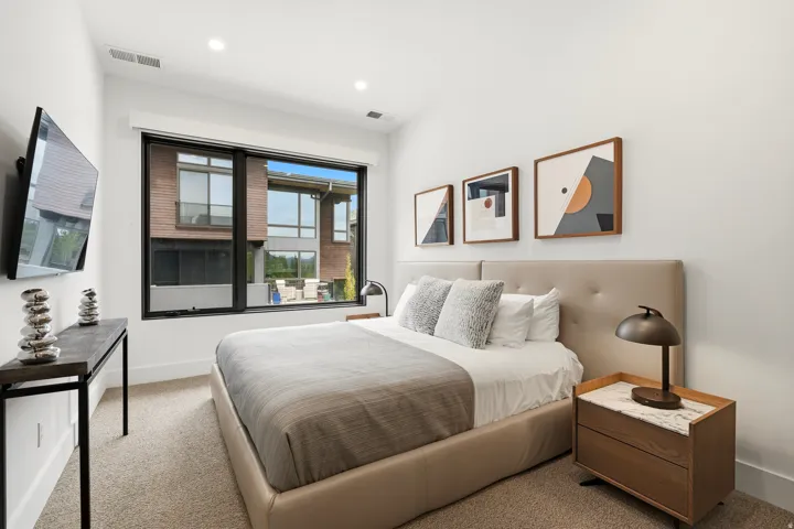 Contemporary bedroom featuring a large picture window, recessed lighting, and neutral wall paint