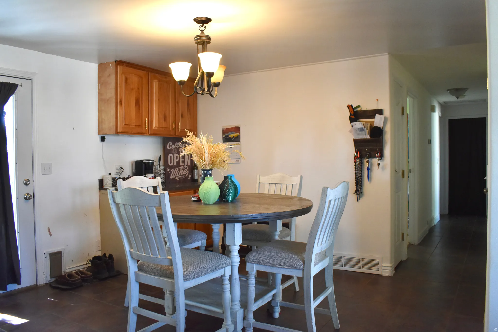 Dining area featuring a central chandelier, wood-finish flooring, and light wood cabinetry